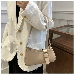 Detail of beige leather baguette bag with silver ring buckle on a white blazer outfit