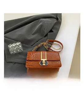 Close-up of brown crocodile embossed leather texture with gold metal chain strap