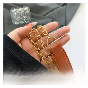 Detailed macro view of a gold-toned metal chain strap with a brown faux leather shoulder pad