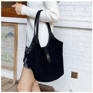 Detail of a black matte tote bag with silver metal buckle and leather shoulder straps
