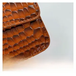 Macro shot of dark brown crocodile embossed leather with high-gloss finish and stitching
