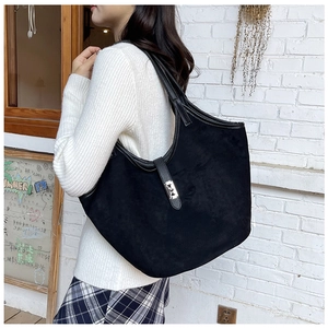 Detail of black suede tote bag with leather strap and silver buckle on white background