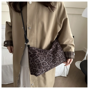 Detail of leopard print tote bag with black leather strap worn with a khaki trench coat