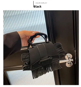 Détail d'un sac à main noir mat avec de longues franges et une poignée demi-ronde