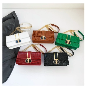 Detailed view of five faux crocodile leather handbags with distinctive round gold buckles