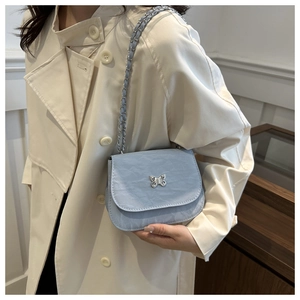 Détail du sac selle bleu clair en similicuir texturé avec boucle papillon argentée élégante