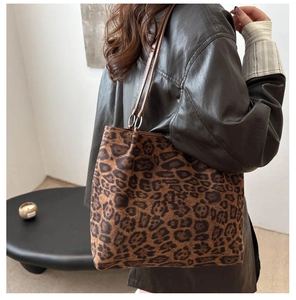 Detailed view of fashionable leopard print tote bag with brown leather straps and metal rings