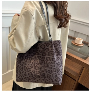 Detailed back view of a large leopard print tote bag worn on shoulder in a cozy setting