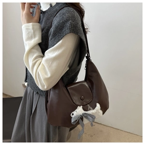 Detailansicht der dunkelbraunen Leder-Halbmondtasche mit süßem weißem Welpen-Patch und Schleife