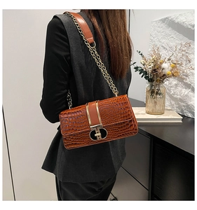 Detail of vintage brown crocodile embossed bag with gold clasp and chain strap