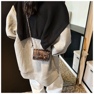 Detailed close-up of a mini leopard print crossbody bag with dual decorative belt buckles