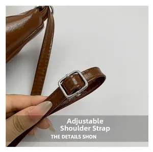 Close-up of brown textured leather bag with adjustable strap and silver metal buckle