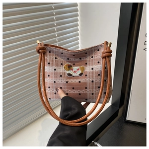 Détail d'un sac à bandoulière rétro à carreaux avec rayures en dentelle et écusson chien