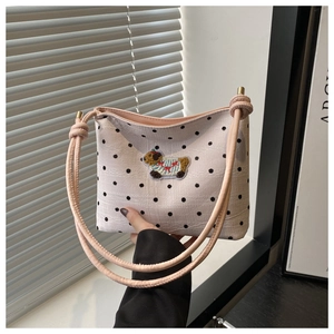 Détail du sac seau en toile beige à pois avec broderie chien et bandoulière à nœuds roses