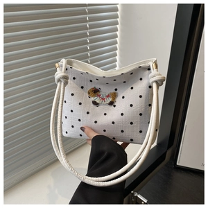 Détail d'un sac à bandoulière blanc à pois avec un écusson brodé de capybara mignon