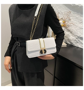 Detail of white crocodile pattern shoulder bag with gold chain and geometric twist lock