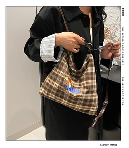 Détail d'un sac en toile à carreaux marron avec motif teckel et bandoulière en cuir