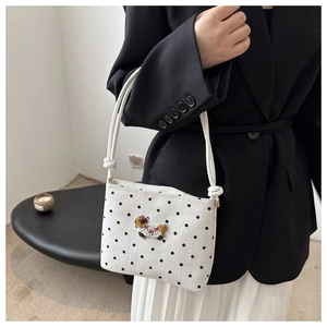 Détail du sac seau en toile à pois noirs avec broderie colorée en forme de chiot