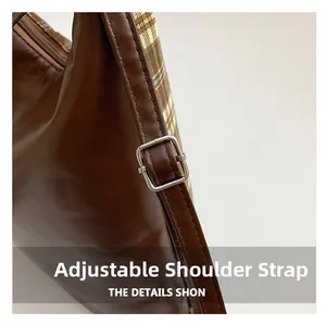 Détail macro de la bandoulière réglable en cuir marron avec boucle sur le sac cabas