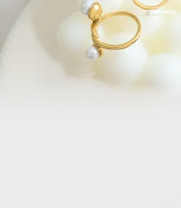 Dettaglio dell'anello a spirale dorato con doppie perle bianche dal design minimalista