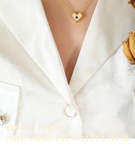 Dettaglio della collana con pendente a cuore dorato con inserto bianco e zircone nero