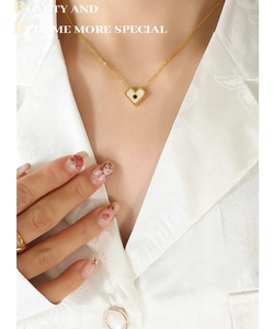 Dettaglio di una collana con ciondolo a cuore dorato con inserto bianco e pietra nera