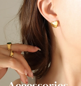 Close-up of minimalist gold heart stud earrings on model with elegant metal texture