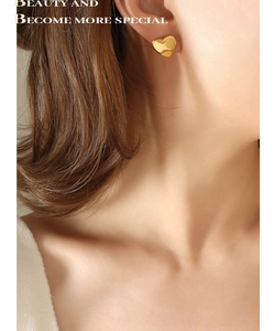 Close-up of a polished golden heart earring worn by a model in minimalist style
