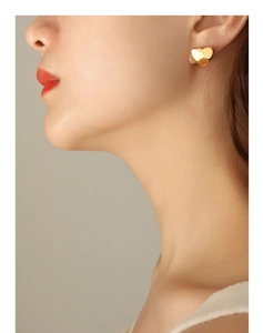 Close-up of minimalist gold-plated heart stud earring worn by model in soft light