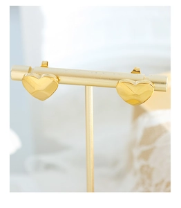 Detailed view of gold-plated titanium heart earrings with geometric faceted texture