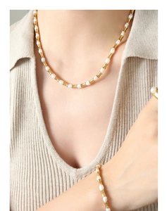 Set di gioielli con maglie dorate a bambù e perle indossato da una modella elegante