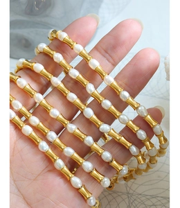 Dettaglio delle maglie in oro a forma di bambù e perle bianche sulla catena di lusso