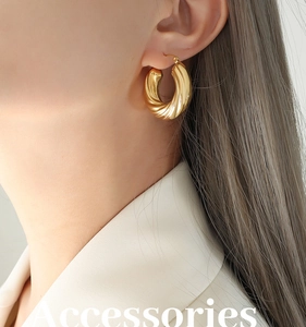 Gros plan de boucles d'oreilles créoles dorées avec détails de texture torsadée fine