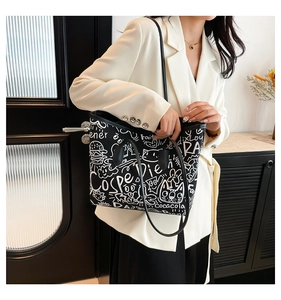 Close-up of the black graffiti canvas tote bag with white hand-drawn prints and leather straps