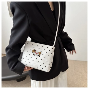 Vue détaillée du sac bandoulière blanc à pois noirs avec broderie chiot sur mannequin
