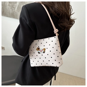 Détail d'un sac seau blanc à pois avec broderie mignonne de capybara et sangle rose