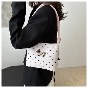 Détail de la broderie d'agneau sur un sac à pois blanc avec bandoulière en cuir rose