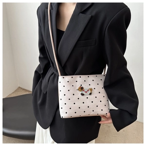 Détail d'un sac seau crème à pois noirs avec broderie de chien et bandoulière fine