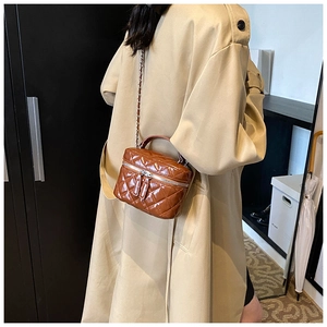 Rear view of woman wearing a brown quilted mini crossbody bag with gold chain and top handle