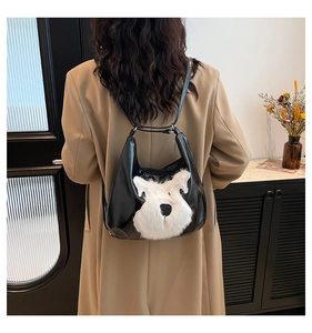 Detail shot of black crescent shoulder bag with fluffy white dog motif on a wool coat