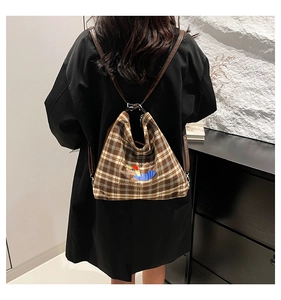 Détail d'un sac à dos vintage à carreaux avec imprimé chiot et lanières en cuir brun