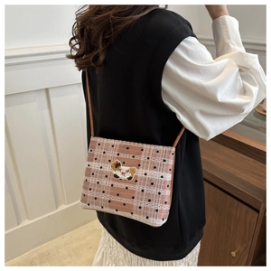 Gros plan du sac bandoulière à carreaux marron avec broderie chien et bordure en dentelle