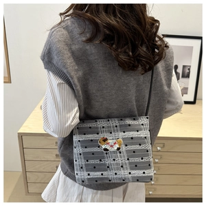 Détail du sac à bandoulière en maille à carreaux gris avec broderie chien et sangle