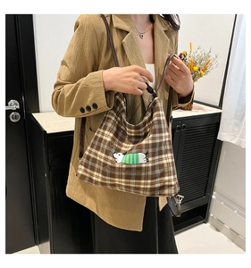 Détail du sac cabas à carreaux avec illustration de chien et bandoulière en cuir brun