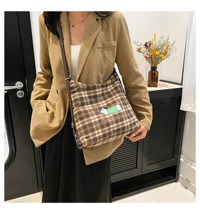 Détail d'un sac cabas à carreaux vintage avec broderie de chien et lanières en cuir