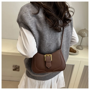 Détail du sac croissant marron café avec boucle en métal doré dans un décor lifestyle
