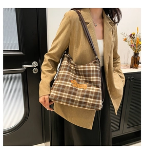 Détail du sac cabas à carreaux avec illustration de chien et bandoulière en cuir marron
