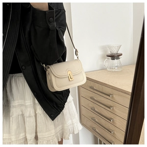 Vue détaillée du sac bandoulière en cuir crème avec un fermoir tournant en métal doré
