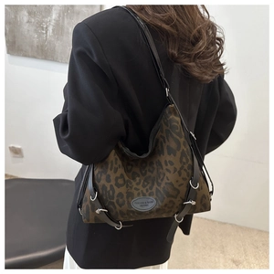 Detail der Tragetasche mit Leopardenmuster, Metallringen und schwarzen Lederriemen