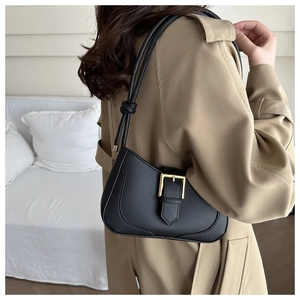 Détail du sac croissant noir avec boucle dorée et bandoulière à nœud style vintage